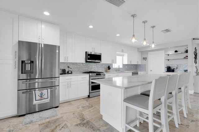 3701 Corsair Ct, New Port Richey, FL 34652 - kitchen featuring appliances with stainless steel finishes, decorative backsplash, a center island, white cabinets, and a breakfast bar