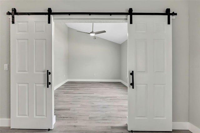 4360 Talco Ave, Spring Hill, FL 34609 - empty room with a barn door, wood finished floors, a ceiling fan, and lofted ceiling