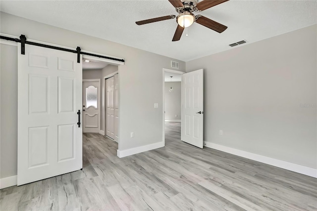 4360 Talco Ave, Spring Hill, FL 34609 - unfurnished bedroom with a barn door, light wood finished floors, a closet, and ceiling fan