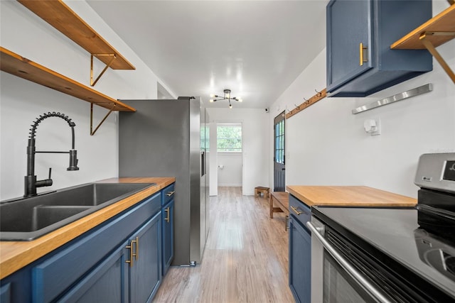 4622 Paloverde Dr, New Port Richey, FL 34652 - kitchen with blue cabinets, appliances with stainless steel finishes, open shelves, wooden counters, and light wood-style floors