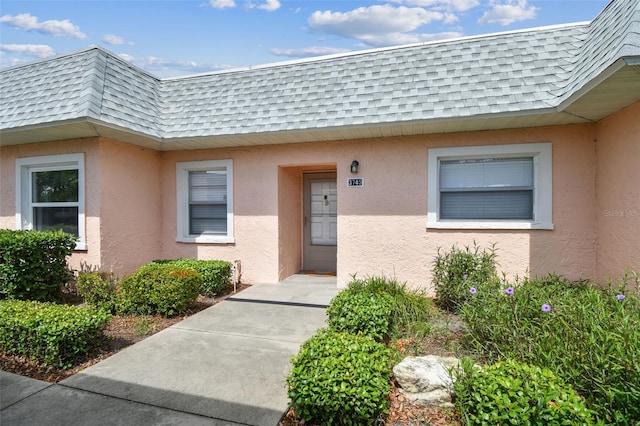 3745 Teeside Dr Unit 3745, New Port Richey, FL 34655 - doorway to property with mansard roof, a shingled roof, and stucco siding