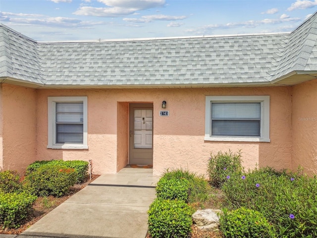 3745 Teeside Dr Unit 3745, New Port Richey, FL 34655 - view of exterior entry featuring a shingled roof, mansard roof, and stucco siding