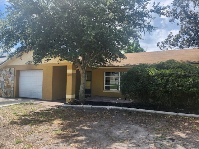 7338 Foxbloom Dr, Port Richey, FL 34668 - obstructed view of property with an attached garage, stucco siding, and driveway