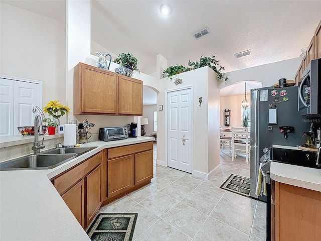 9431 Spring Hill Dr, Spring Hill, FL 34608 - kitchen with arched walkways, stainless steel microwave, brown cabinets, light countertops, and vaulted ceiling