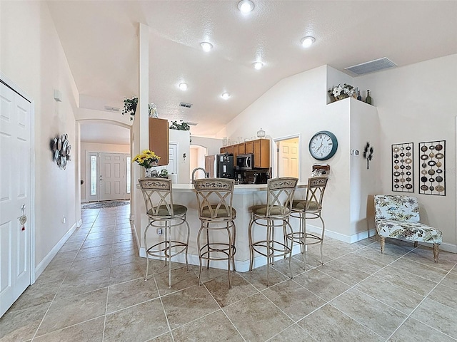 9431 Spring Hill Dr, Spring Hill, FL 34608 - kitchen featuring stainless steel microwave, freestanding refrigerator, a breakfast bar, arched walkways, and a peninsula