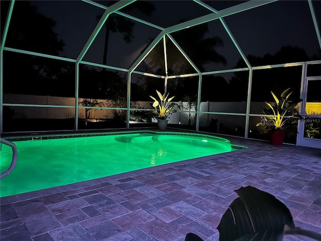 9431 Spring Hill Dr, Spring Hill, FL 34608 - pool at night with glass enclosure and a patio