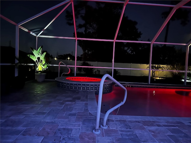 9431 Spring Hill Dr, Spring Hill, FL 34608 - pool at night with glass enclosure, an outdoor pool, a patio area, and an in-ground hot tub