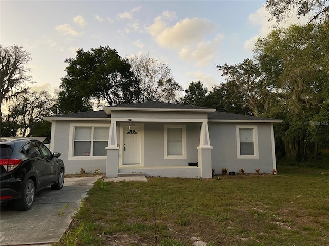 12419 Lamont Ave, New Port Richey, FL 34654 - view of front facade featuring a front yard, stucco siding, covered porch, and a shingled roof