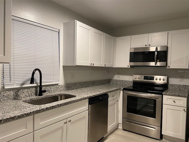 12419 Lamont Ave, New Port Richey, FL 34654 - kitchen featuring appliances with stainless steel finishes, white cabinetry, light stone countertops, and light wood finished floors