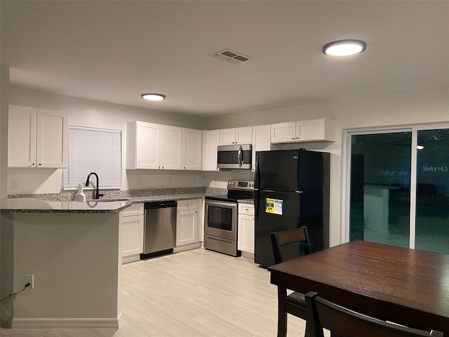 12419 Lamont Ave, New Port Richey, FL 34654 - kitchen featuring appliances with stainless steel finishes, dark stone countertops, and white cabinetry