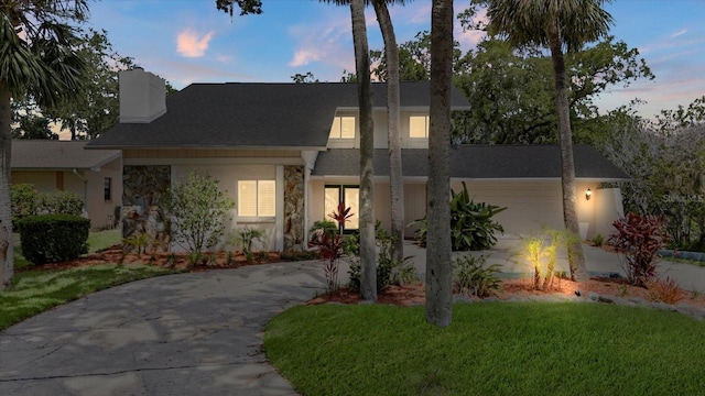 4439 Reeves Rd, New Port Richey, FL 34652 - view of front of property with driveway, a chimney, stone siding, stucco siding, and a yard