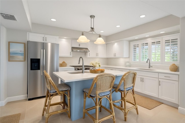 4439 Reeves Rd, New Port Richey, FL 34652 - kitchen with stainless steel refrigerator with ice dispenser, under cabinet range hood, light countertops, white cabinetry, and a center island with sink