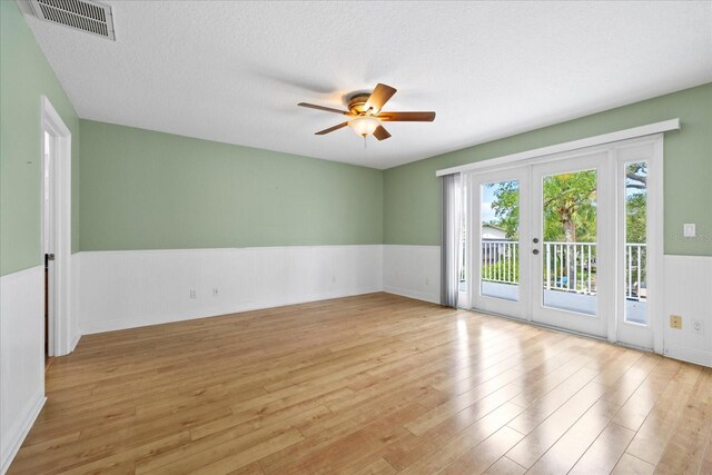 4439 Reeves Rd, New Port Richey, FL 34652 - spare room with a wainscoted wall, light wood-style floors, french doors, ceiling fan, and a textured ceiling