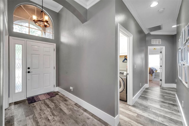 9309 Edistro Pl, New Port Richey, FL 34654 - foyer entrance featuring crown molding, light wood-style floors, a chandelier, washer / clothes dryer, and plenty of natural light