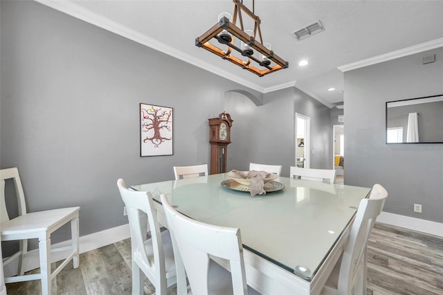9309 Edistro Pl, New Port Richey, FL 34654 - dining room featuring light wood-style flooring, ornamental molding, a chandelier, arched walkways, and recessed lighting