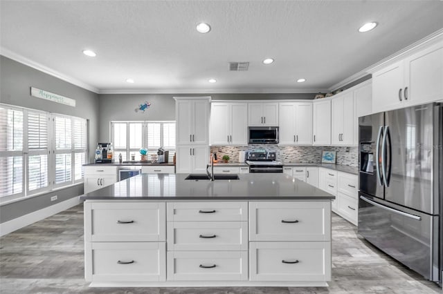 9309 Edistro Pl, New Port Richey, FL 34654 - kitchen with stainless steel appliances, ornamental molding, backsplash, an island with sink, and light wood-style flooring