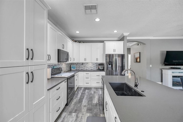 9309 Edistro Pl, New Port Richey, FL 34654 - kitchen featuring black microwave, stainless steel fridge with ice dispenser, range with electric stovetop, arched walkways, and light wood-style flooring