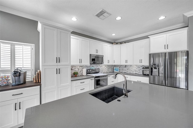 9309 Edistro Pl, New Port Richey, FL 34654 - kitchen featuring stainless steel appliances, ornamental molding, tasteful backsplash, dark countertops, and white cabinetry