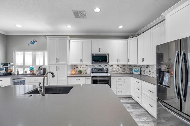 9309 Edistro Pl, New Port Richey, FL 34654 - kitchen featuring stainless steel appliances, crown molding, decorative backsplash, wine cooler, and white cabinets