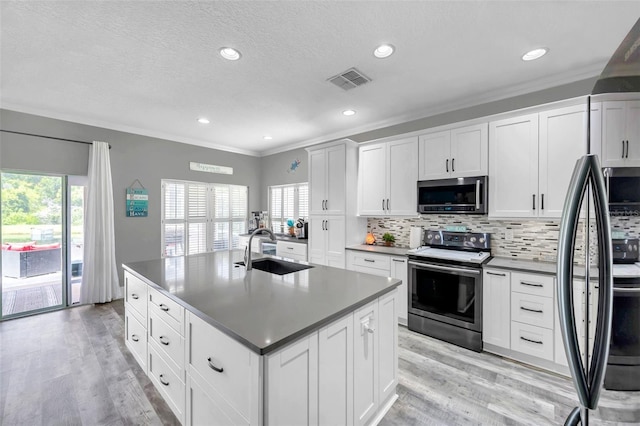 9309 Edistro Pl, New Port Richey, FL 34654 - kitchen featuring stainless steel appliances, crown molding, light wood finished floors, tasteful backsplash, and a kitchen island with sink
