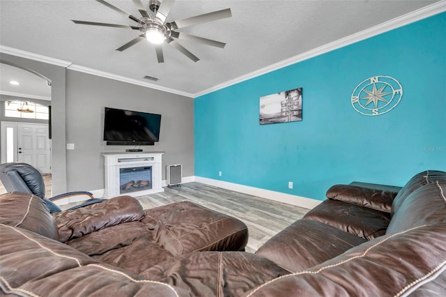 9309 Edistro Pl, New Port Richey, FL 34654 - living room featuring arched walkways, wood finished floors, ceiling fan, ornamental molding, and a fireplace