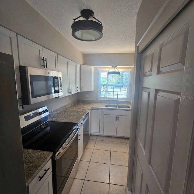 2200 S Palmetto Ave Unit E050, South Daytona, FL 32119 - kitchen with appliances with stainless steel finishes, white cabinetry, a textured ceiling, stone countertops, and light tile patterned flooring