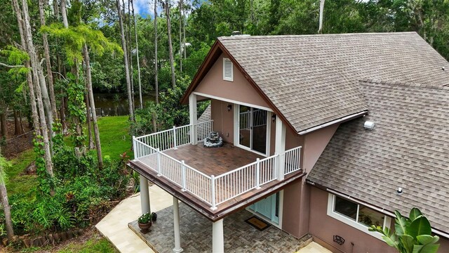 2202 Amity Ct, New Port Richey, FL 34655 - rear view of house with roof with shingles, stucco siding, a patio area, and view of scattered trees