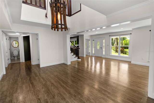 2202 Amity Ct, New Port Richey, FL 34655 - unfurnished living room with stairway, a chandelier, wood finished floors, and crown molding