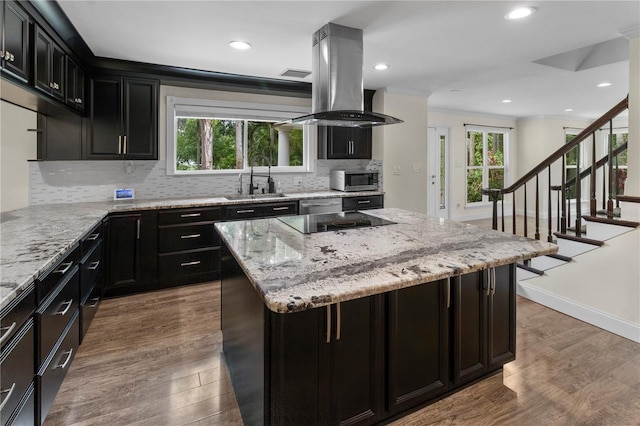 2202 Amity Ct, New Port Richey, FL 34655 - kitchen featuring island range hood, dark cabinets, backsplash, light stone counters, and recessed lighting