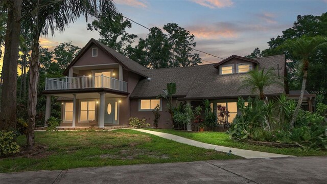 2202 Amity Ct, New Port Richey, FL 34655 - view of front of property featuring a balcony, stucco siding, a yard, and roof with shingles