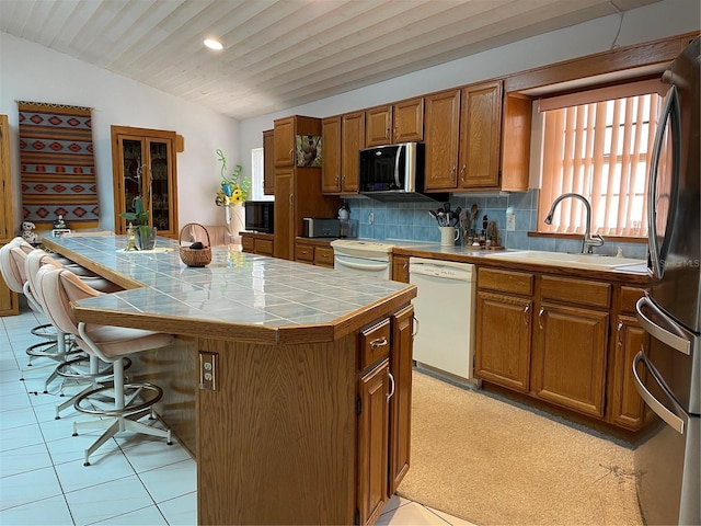 20971 Negril Ct, Lutz, FL 33558 - kitchen with white appliances, tile countertops, lofted ceiling, brown cabinets, and a center island