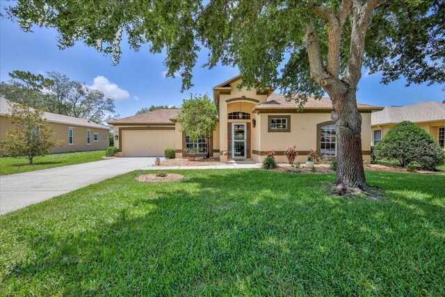 9406 Burnam Dr, Weeki Wachee, FL 34613 - mediterranean / spanish-style home featuring stucco siding, an attached garage, driveway, and a front yard