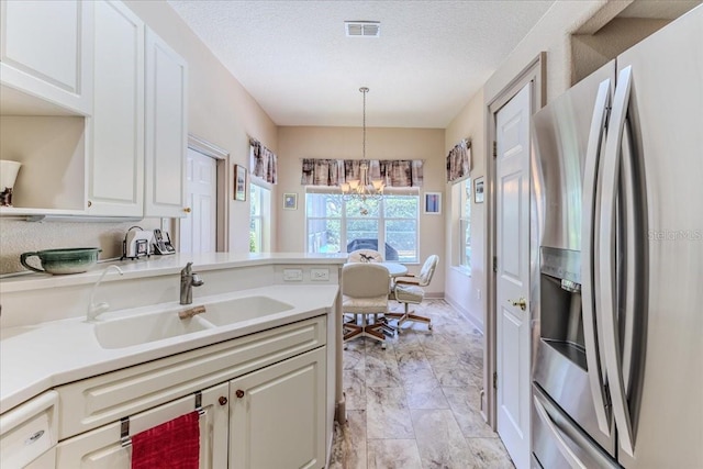 9406 Burnam Dr, Weeki Wachee, FL 34613 - kitchen with stainless steel refrigerator with ice dispenser, a chandelier, light countertops, pendant lighting, and a textured ceiling