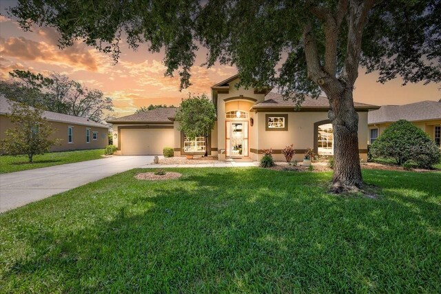 9406 Burnam Dr, Weeki Wachee, FL 34613 - view of front of property with stucco siding, driveway, a yard, and a garage