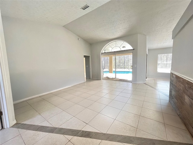 10060 Chip Ln, New Port Richey, FL 34654 - unfurnished room featuring light tile patterned flooring, a textured ceiling, and vaulted ceiling