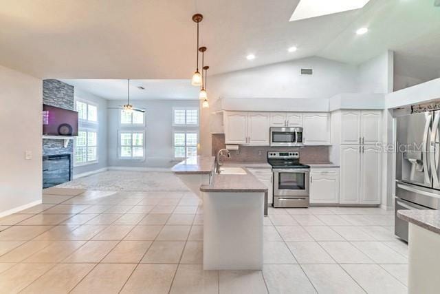 10060 Chip Ln, New Port Richey, FL 34654 - kitchen featuring stainless steel appliances, a peninsula, open floor plan, white cabinets, and light tile patterned floors