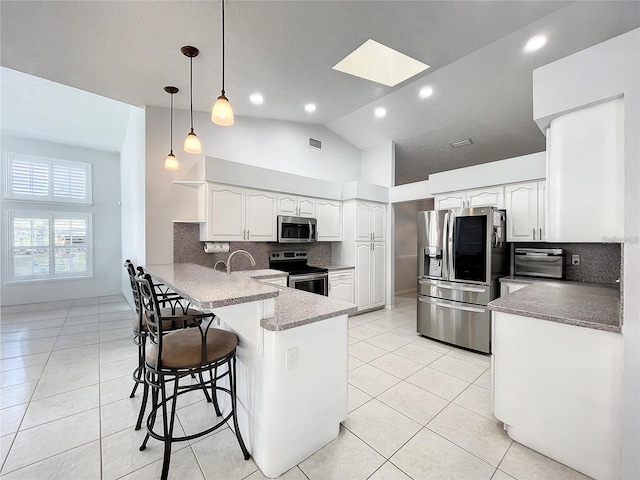10060 Chip Ln, New Port Richey, FL 34654 - kitchen featuring appliances with stainless steel finishes, a peninsula, tasteful backsplash, light tile patterned flooring, and high vaulted ceiling