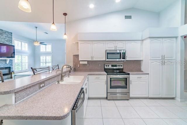 10060 Chip Ln, New Port Richey, FL 34654 - kitchen featuring appliances with stainless steel finishes, a peninsula, decorative backsplash, white cabinetry, and lofted ceiling