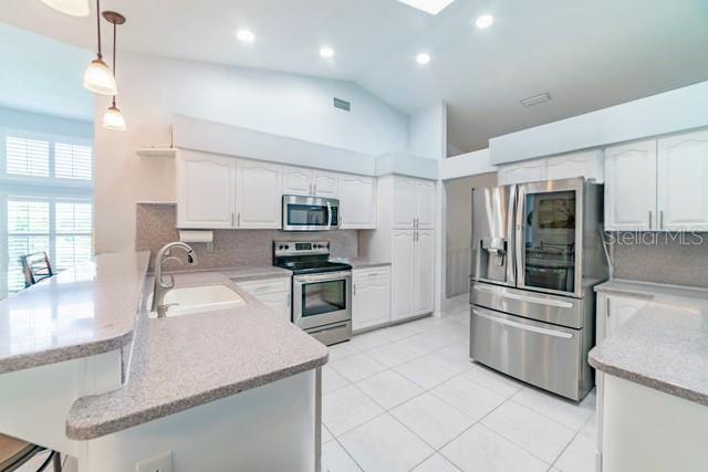 10060 Chip Ln, New Port Richey, FL 34654 - kitchen featuring appliances with stainless steel finishes, a peninsula, open shelves, hanging light fixtures, and backsplash