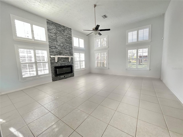 10060 Chip Ln, New Port Richey, FL 34654 - unfurnished living room with light tile patterned flooring, a ceiling fan, a fireplace, a towering ceiling, and a textured ceiling