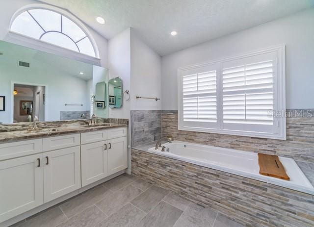 10060 Chip Ln, New Port Richey, FL 34654 - full bathroom with lofted ceiling, plenty of natural light, a garden tub, and vanity