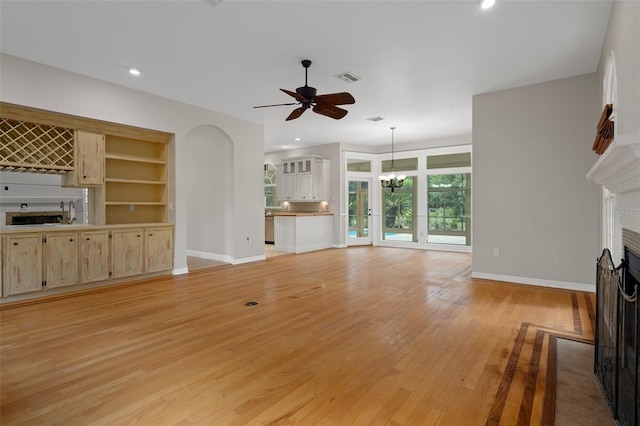 7268 Crystal Spring Run, Weeki Wachee, FL 34607 - unfurnished living room with a fireplace, light wood finished floors, a chandelier, a ceiling fan, and recessed lighting