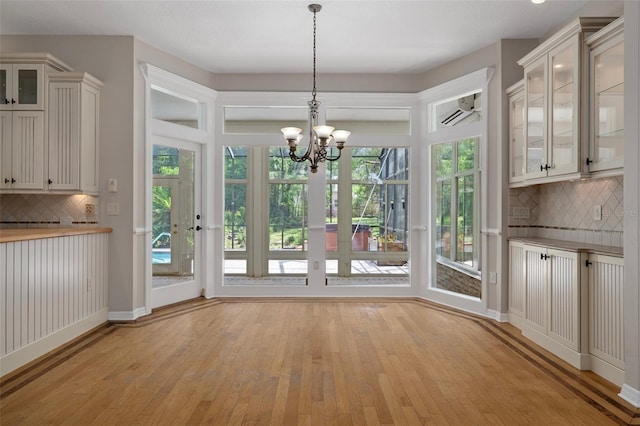 7268 Crystal Spring Run, Weeki Wachee, FL 34607 - unfurnished dining area featuring light wood-style flooring, a chandelier, and a wall mounted air conditioner