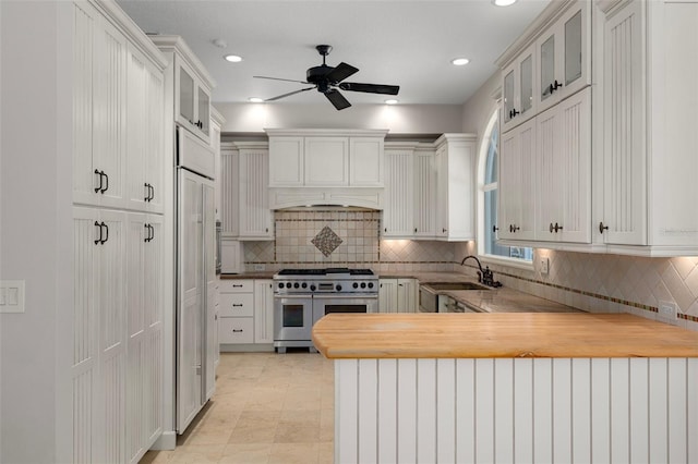 7268 Crystal Spring Run, Weeki Wachee, FL 34607 - kitchen featuring range with two ovens, a peninsula, ceiling fan, premium range hood, and backsplash
