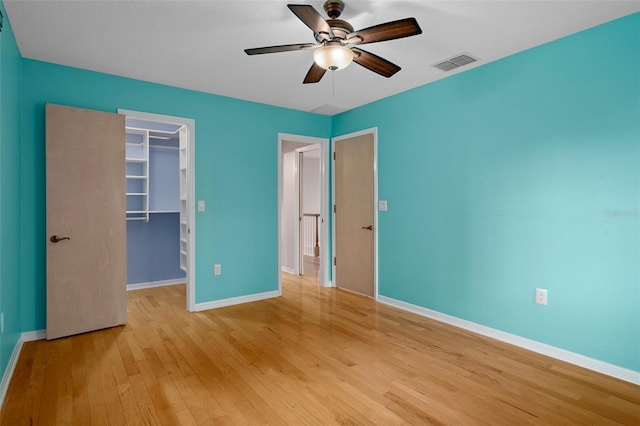 7268 Crystal Spring Run, Weeki Wachee, FL 34607 - unfurnished bedroom with light wood-type flooring, a walk in closet, a closet, and a ceiling fan