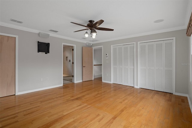 7268 Crystal Spring Run, Weeki Wachee, FL 34607 - unfurnished bedroom with two closets, ornamental molding, light wood-type flooring, and a ceiling fan