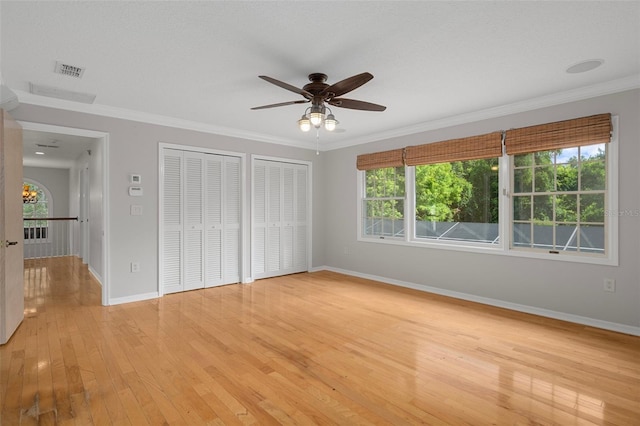 7268 Crystal Spring Run, Weeki Wachee, FL 34607 - unfurnished bedroom featuring multiple closets, light wood-type flooring, ornamental molding, and ceiling fan