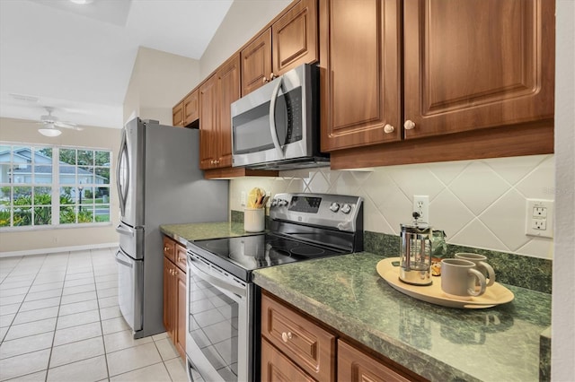 11418 Tee Time Cir, New Port Richey, FL 34654 - kitchen with stainless steel appliances, dark countertops, brown cabinets, light tile patterned flooring, and vaulted ceiling