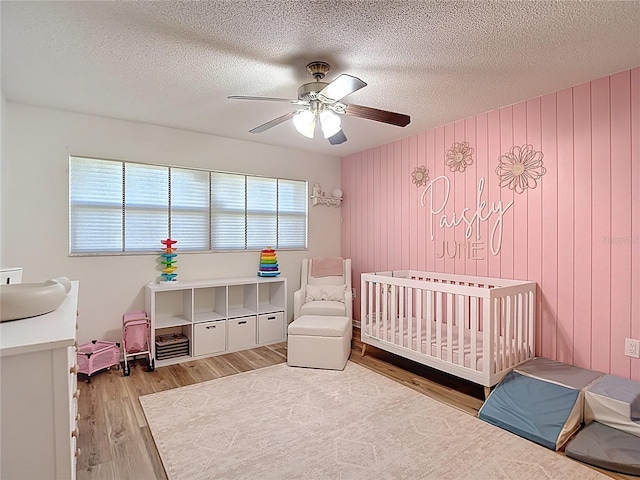 9425 Sterling Ln, Port Richey, FL 34668 - bedroom featuring wood finished floors, a textured ceiling, a ceiling fan, and a crib