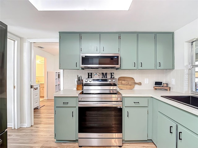 9425 Sterling Ln, Port Richey, FL 34668 - kitchen featuring appliances with stainless steel finishes, light countertops, light wood finished floors, and backsplash